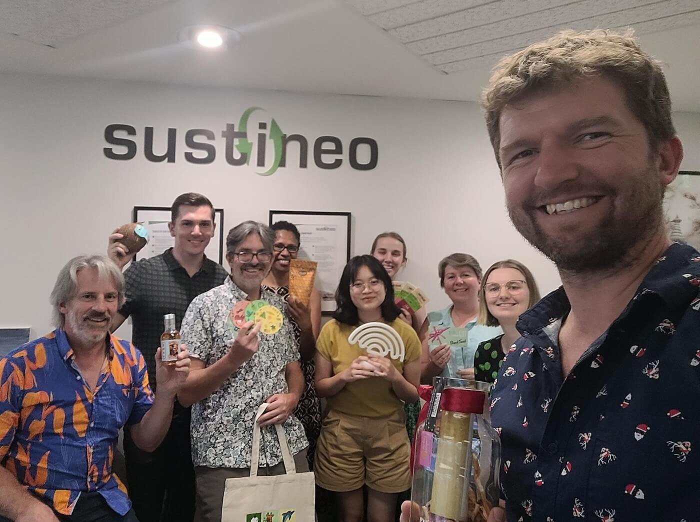 Selfie of the Sustineo team smiling under a 'sustineo' sign