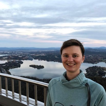 Nina Davis smiling on the viewing deck of Telstra Tower, with Lake Burley Griffin in the background