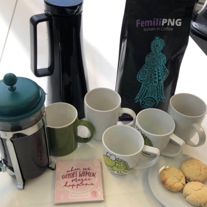 Photo of our new coffee set up: plunger, thermal jug, Femili PNG coffee, some mugs, plus homemade biscuits and a coaster that says "when we support women, magic happens"